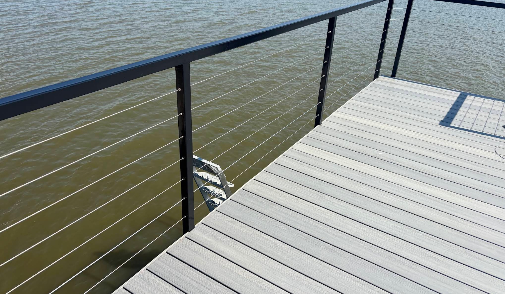 Composite dock decking with black aluminum posts, stainless cable railing and a swim ladder